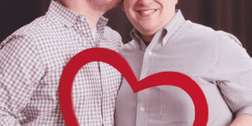 couple holding a paper heart and kissing