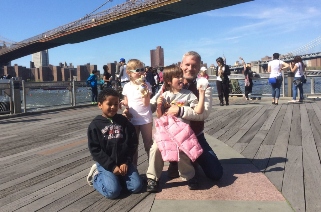 Dad on a boardwalk near a bridge with his son and two daughters eating ice cream cones