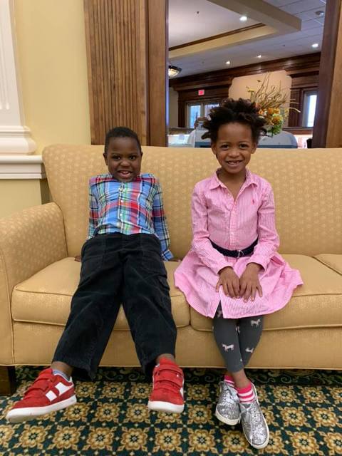 Young brother and sister dressed up and sitting on a couch