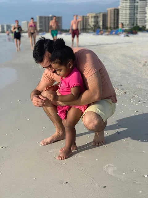 father and daughter collecting shells on the beach