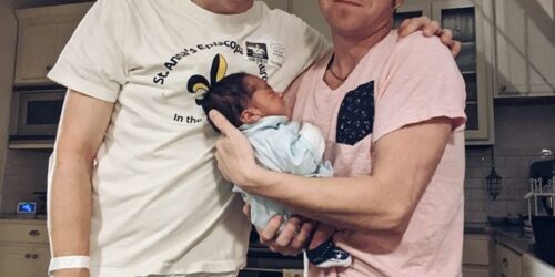 Two men holding a newborn