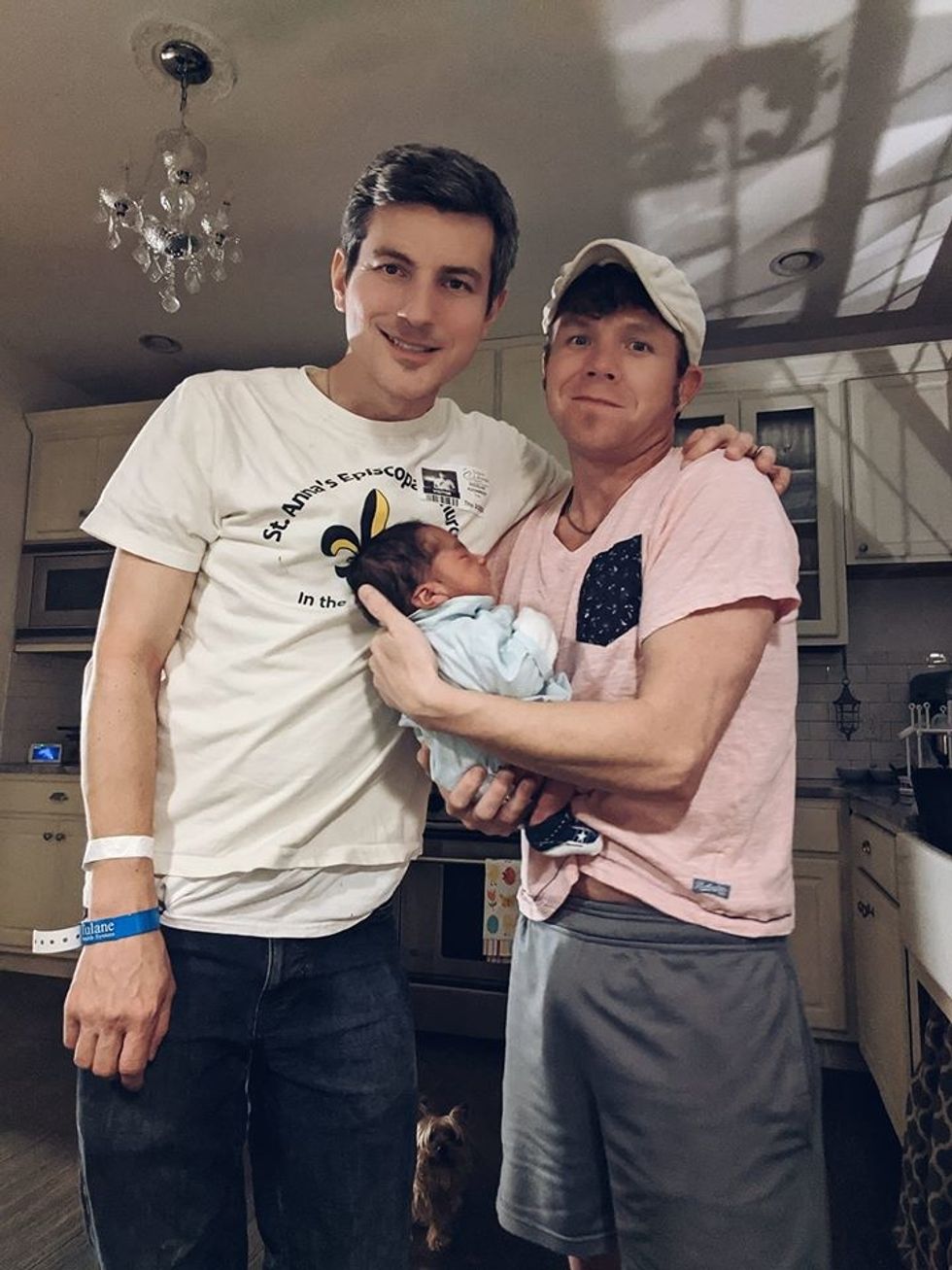 Two men holding a newborn