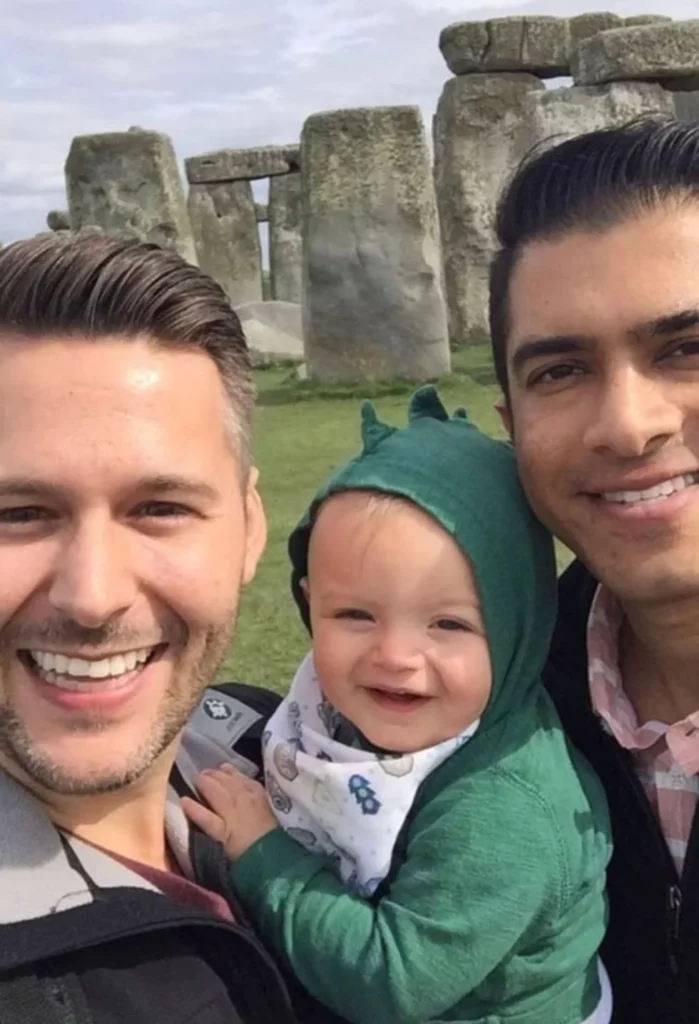 two dads posing with their son at Stonehenge