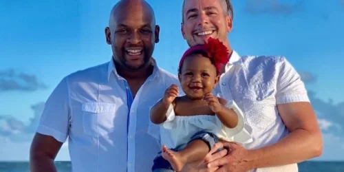 Two gay dads holding a baby