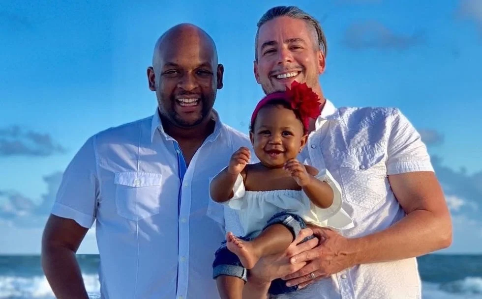 Two gay dads holding a baby