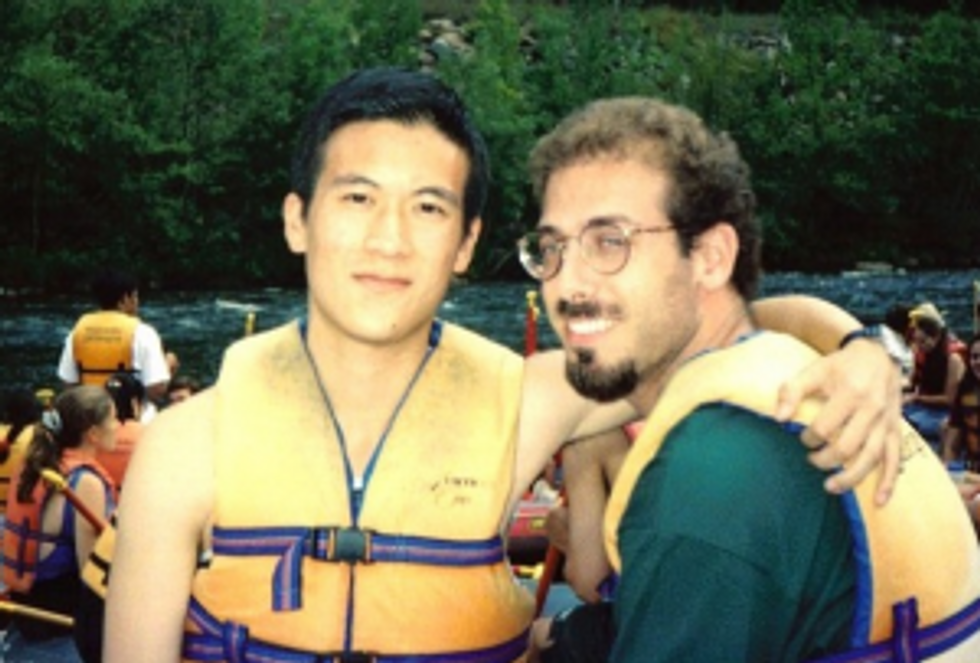 two men posing wearing life jackets on a white water rafting trip