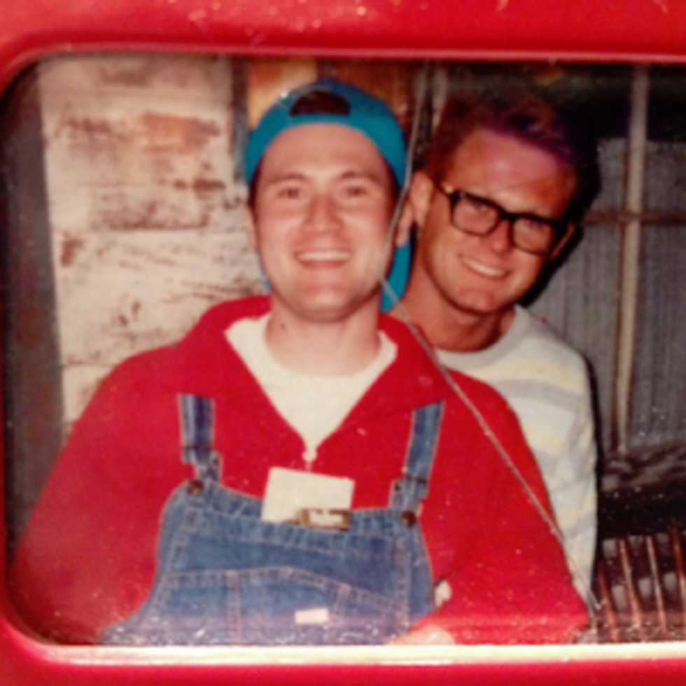 Two men smiling. One wearing jean overalls