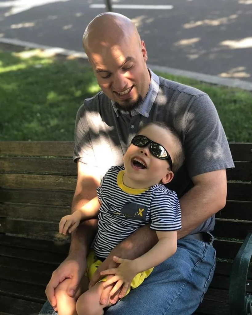 Father and son sitting on bench together smiling
