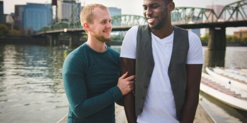 gay couple posing in front of a bridge