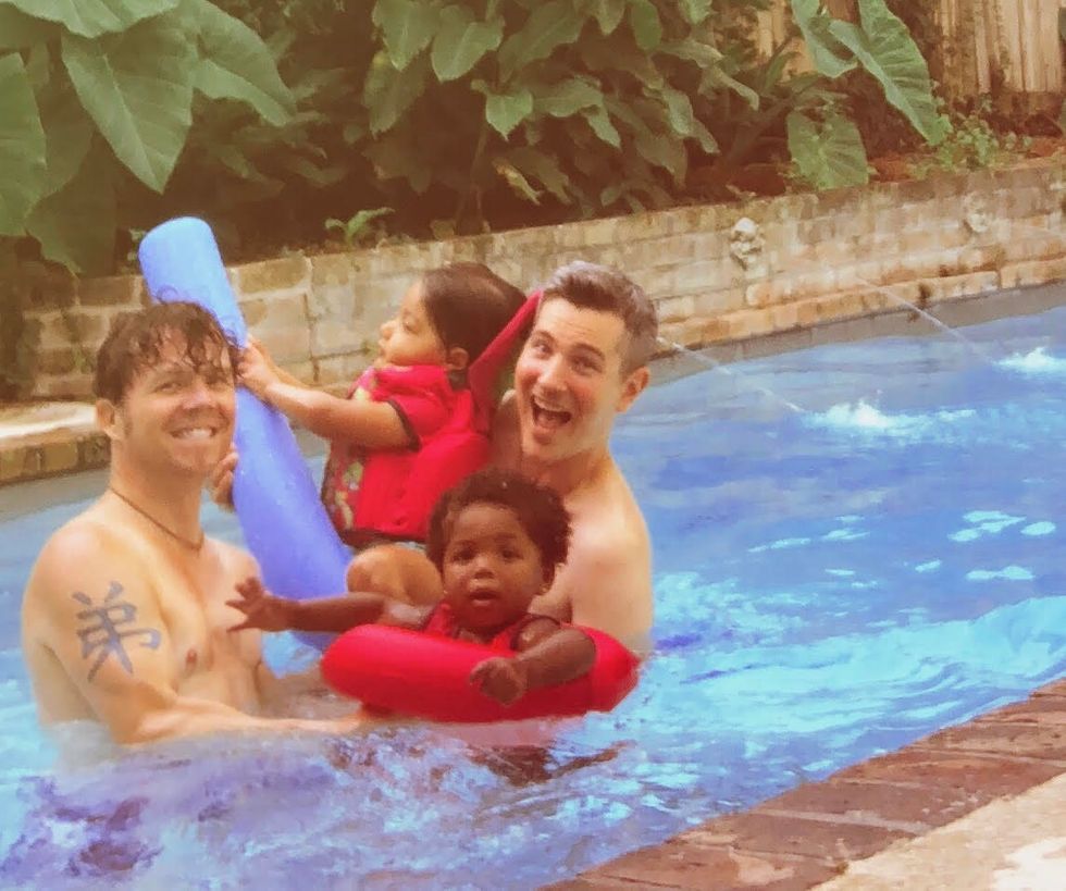 two dads and their daughters playing in a pool
