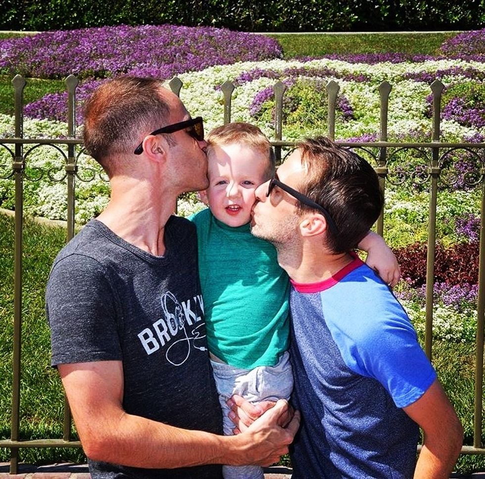 Fathers kissing their son on his cheeks
