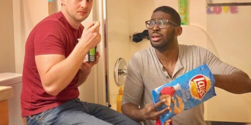 Photo of two dads pretending to hide in their bathroom eating chips and ice cream