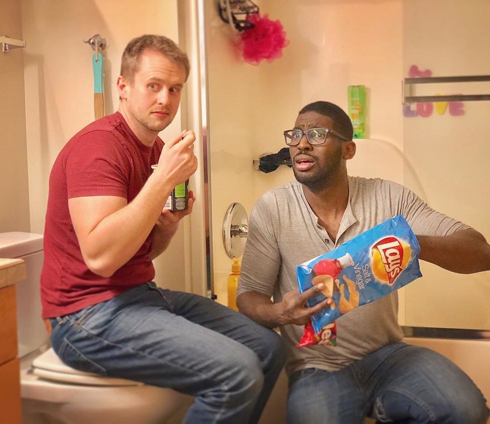 Photo of two dads pretending to hide in their bathroom eating chips and ice cream