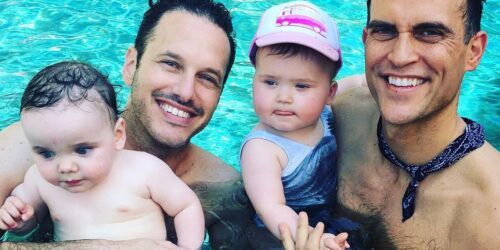 two dads in the pool with their two children