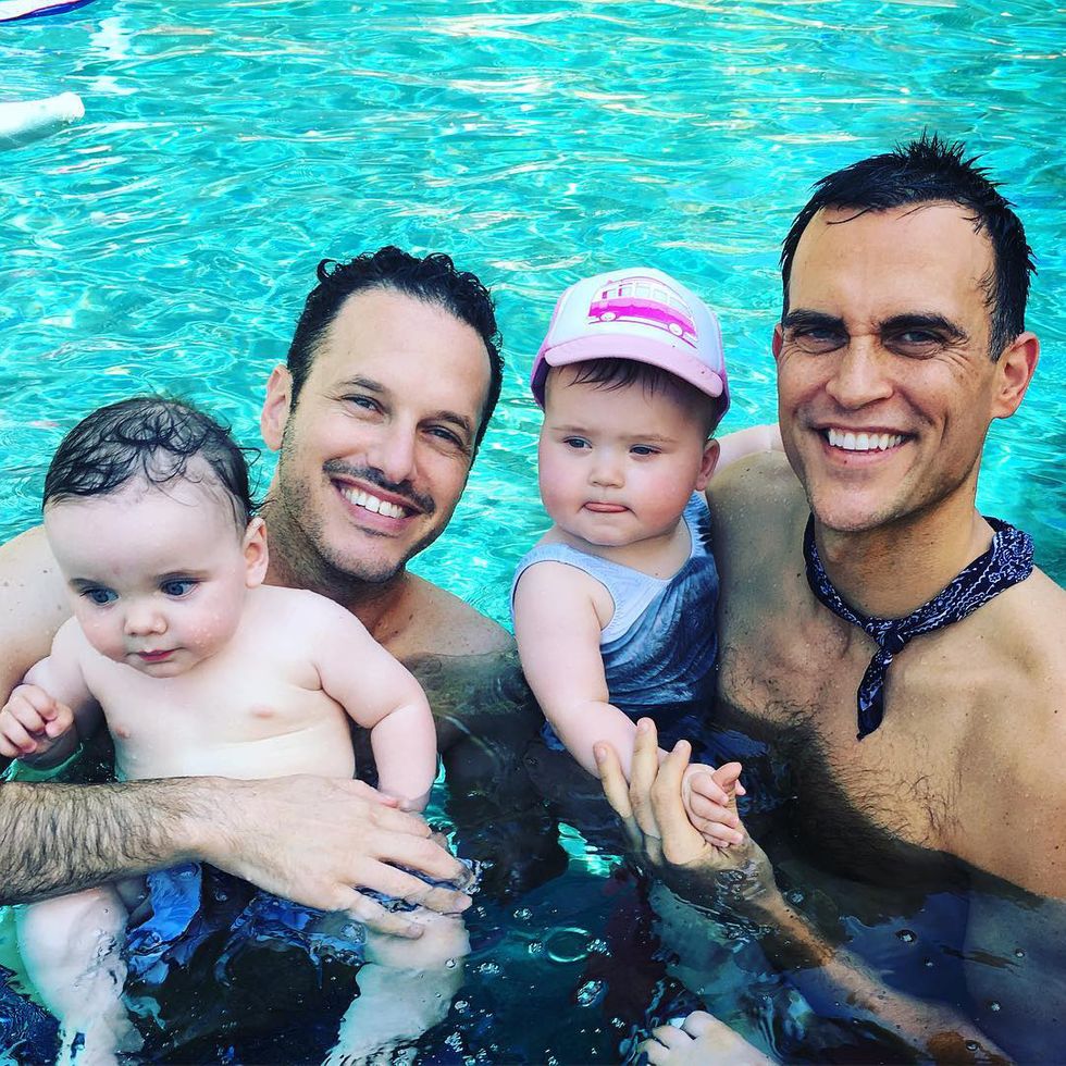 two dads in the pool with their two children