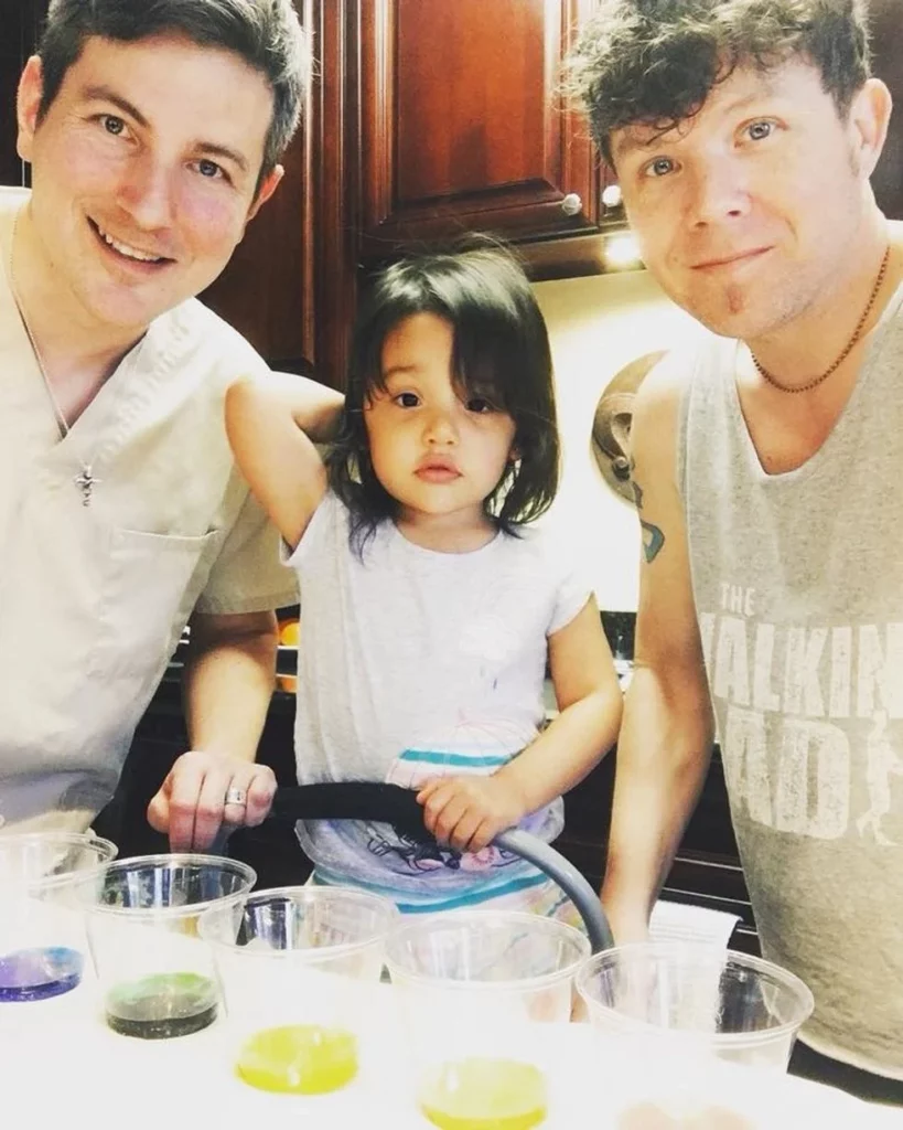 Little girl standing at the kitchen counter with her dads.