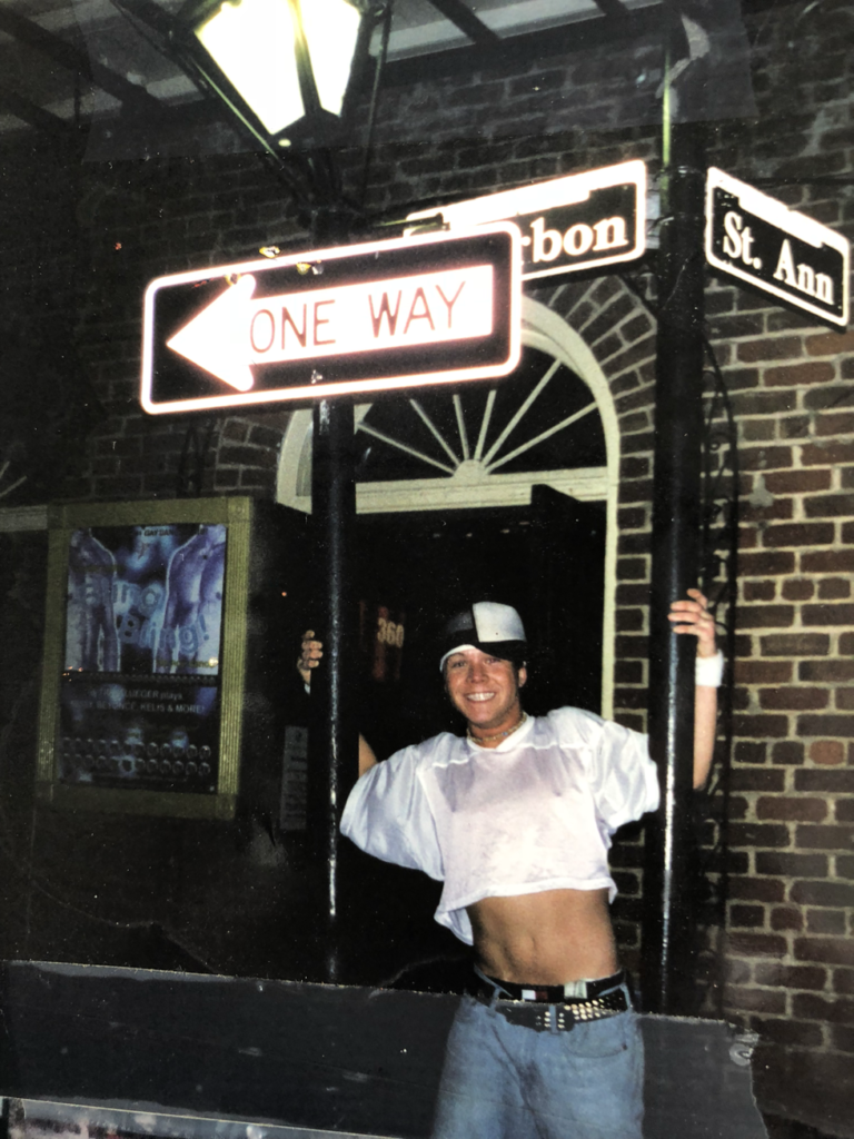 Man posing for picture with Bourbon Street street sign