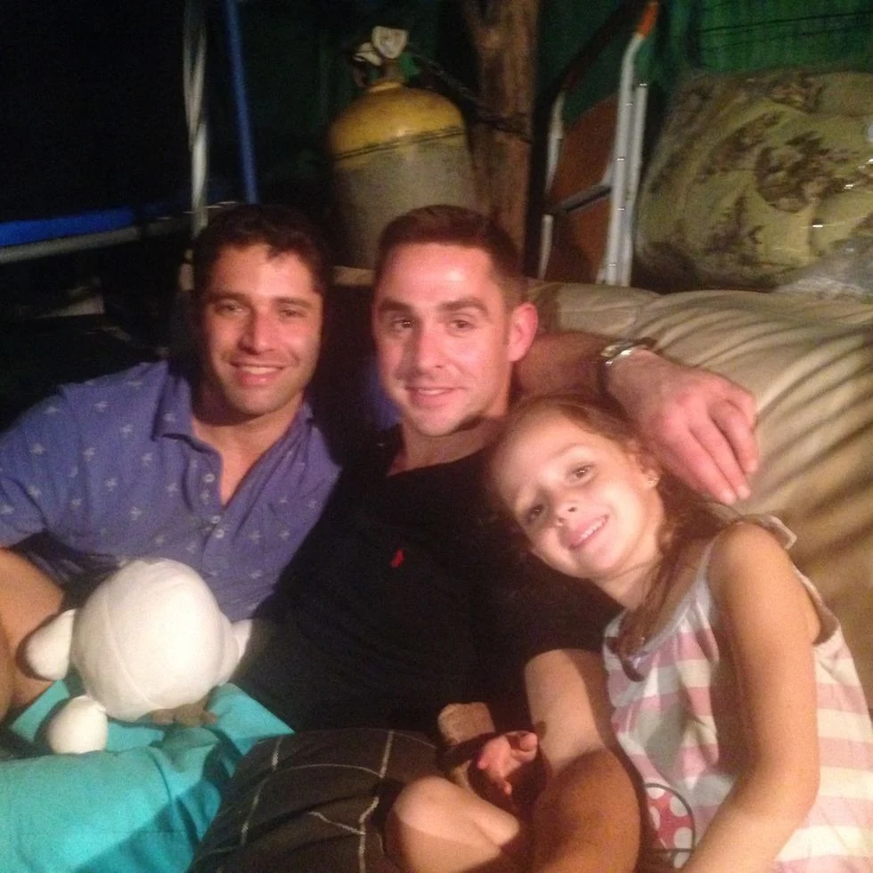 Two men and a little girl sitting on a couch