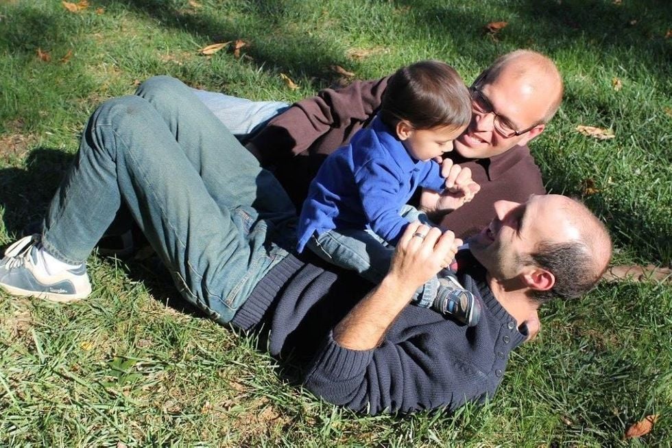 two dads with their son on the lawn