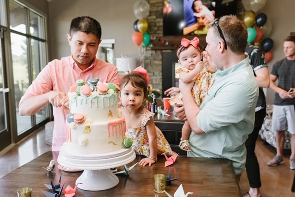 Father cutting his daughter's birthday cake while husband birthday girl and other daughter look on.