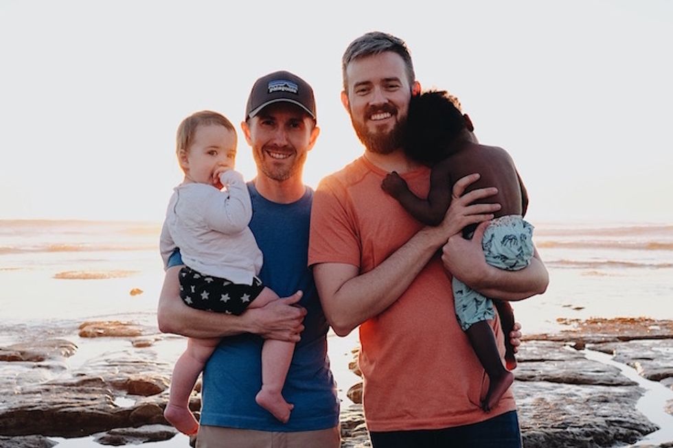 Two foster dads with their two children on the beach