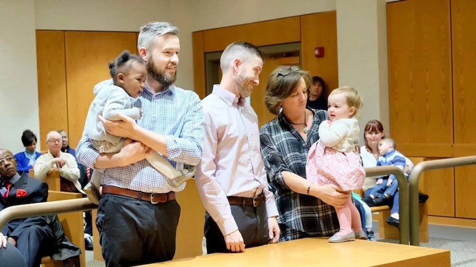 Two dads with their two children on adoption day