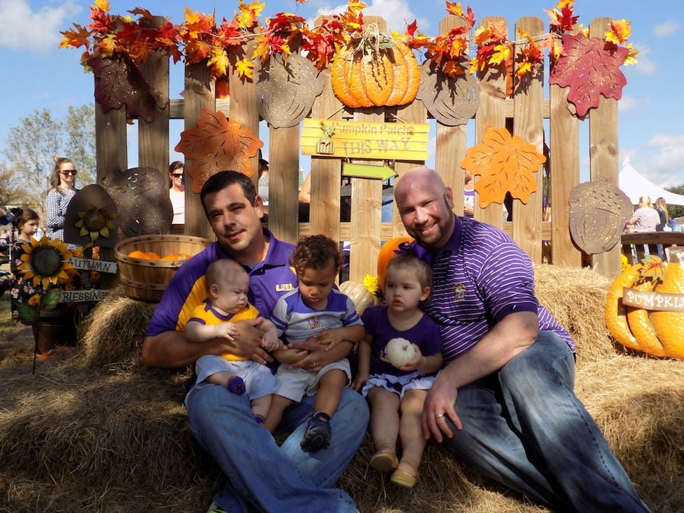 two gay foster dads posing with their three children at a pumpkin patch