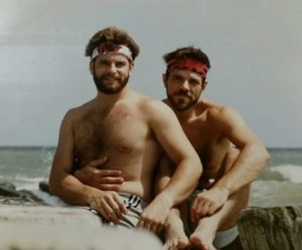 Two men on the beach shirtless with bandanas around their heads