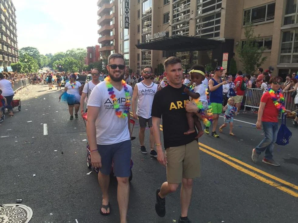 Two dads and their children marching in pride parade