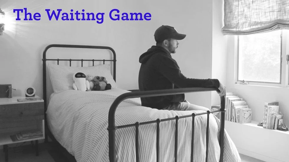 Black and white photo of a father sitting on a child's bed with the title The Waiting Game