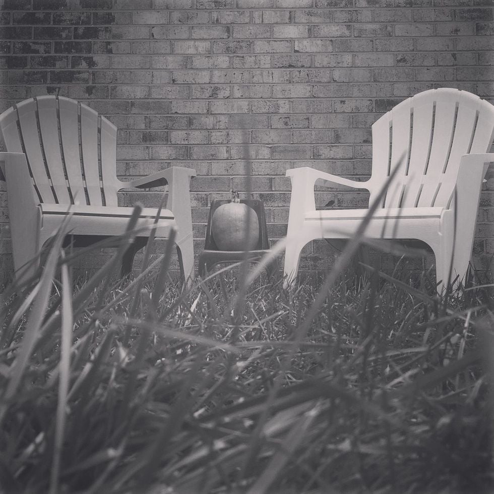 two adirondeck chairs with a pumpking in between