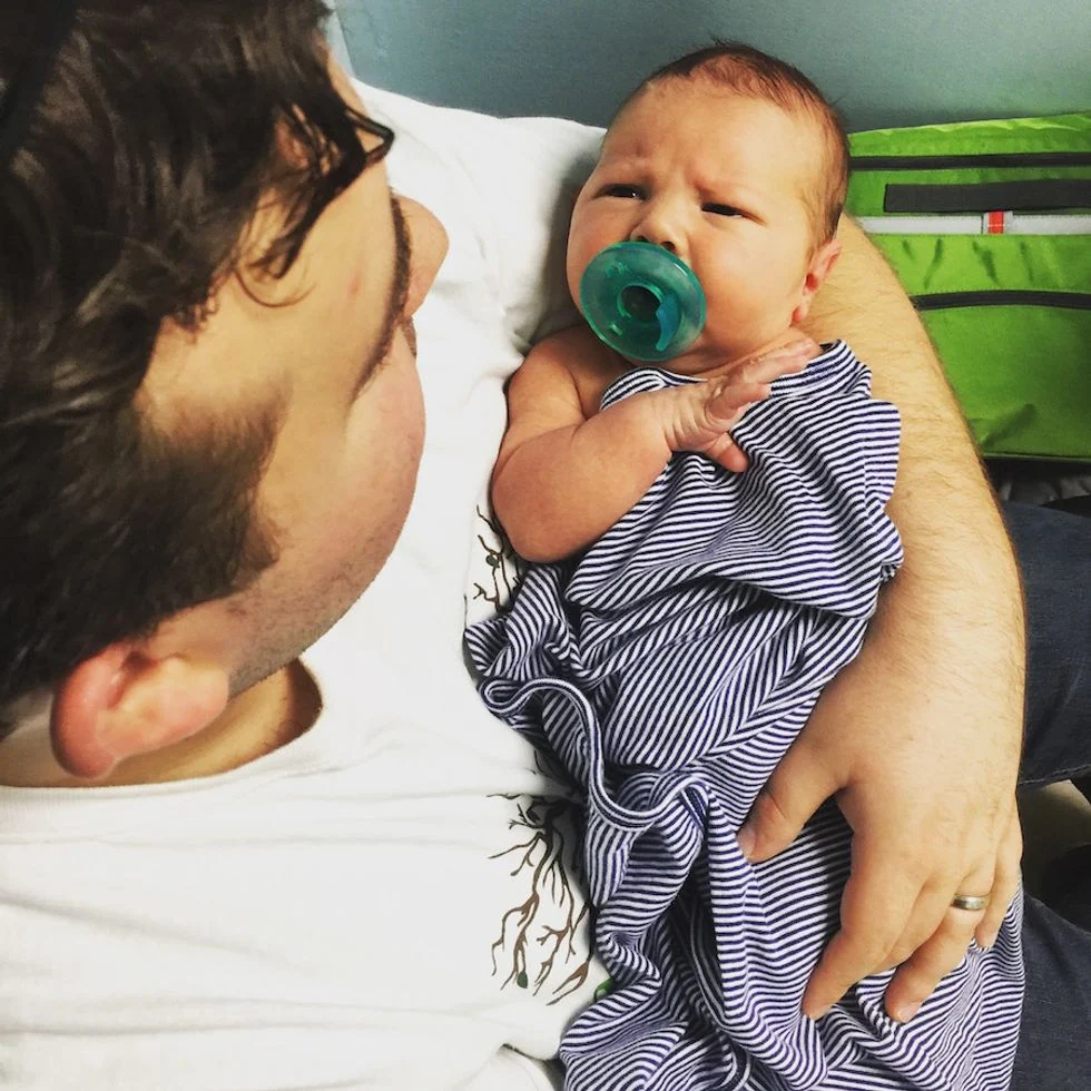Father holding newborn son with a pacifier