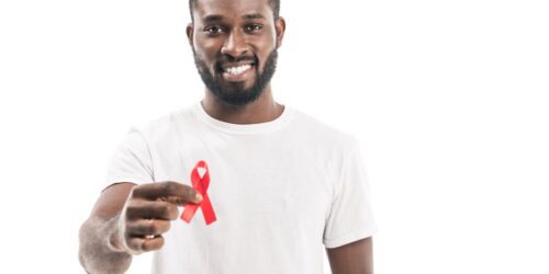 Black man in white tshirt holding a red ribbon
