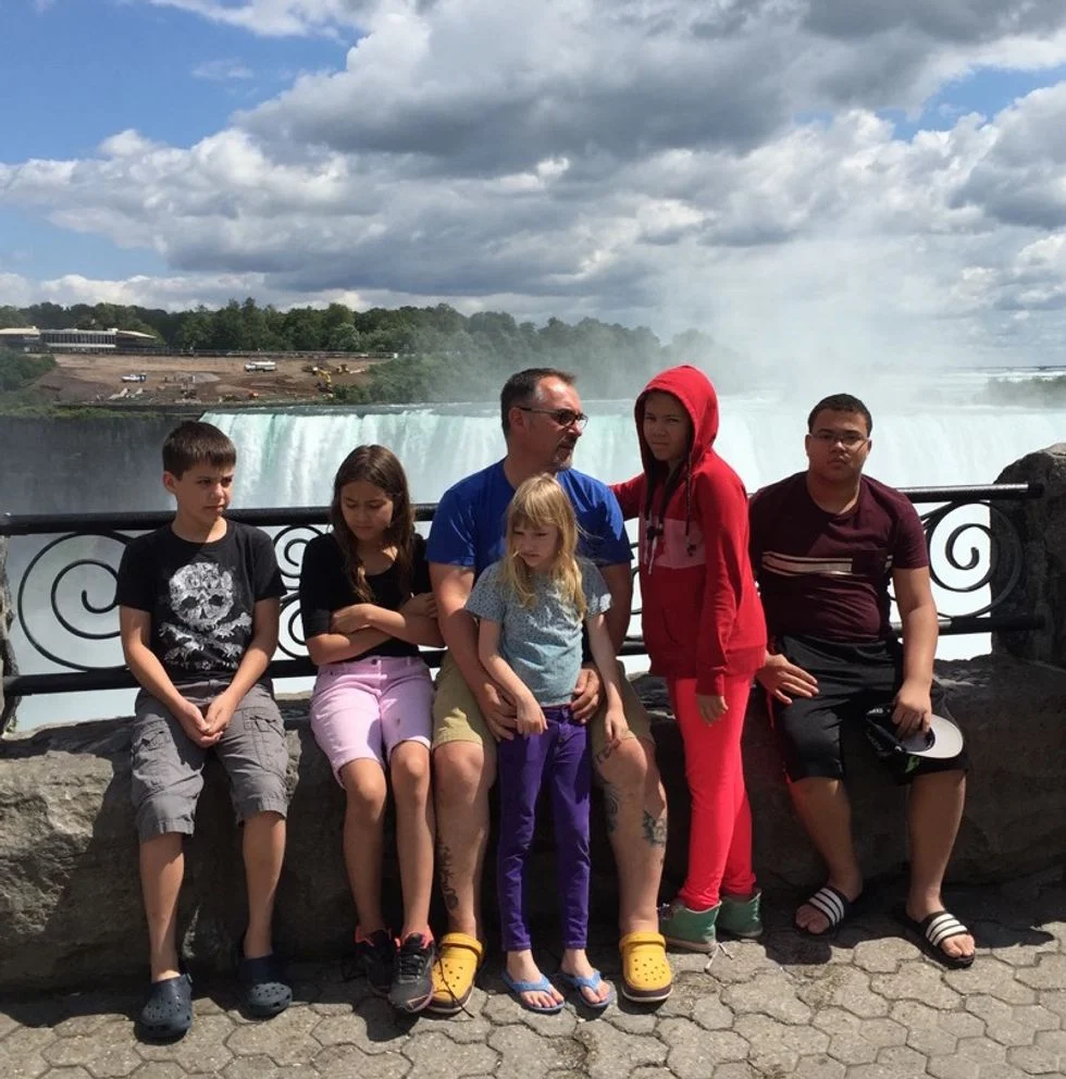 Dad and his five children posing in front of Niagra Falls