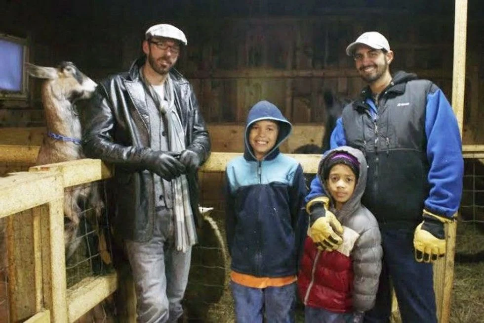 Two foster dads in their barn with their sons