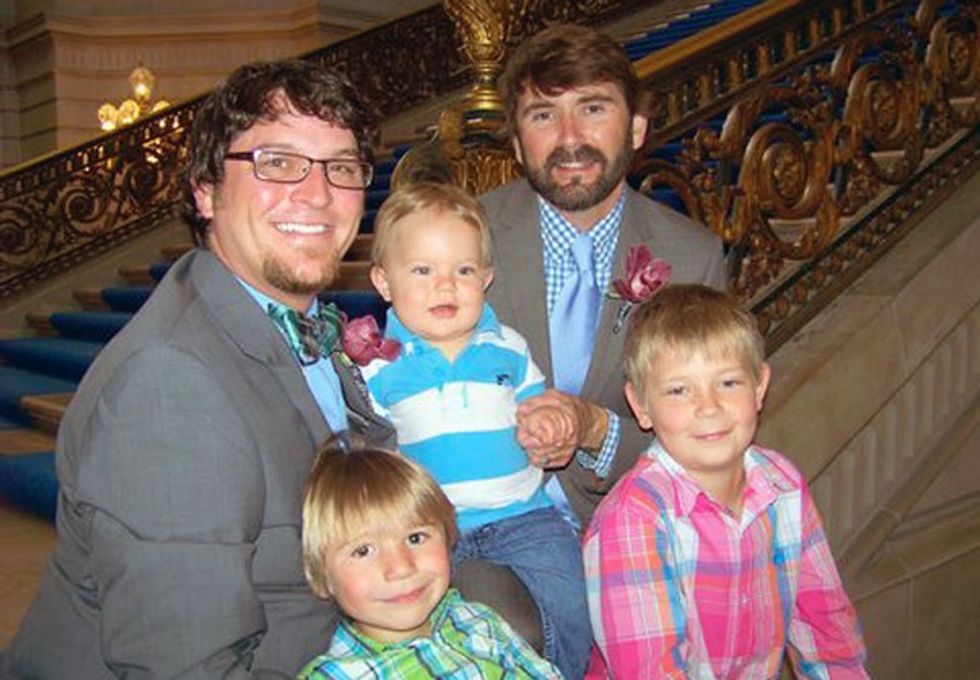 two fathers dressed up in suits posing with their three young sons