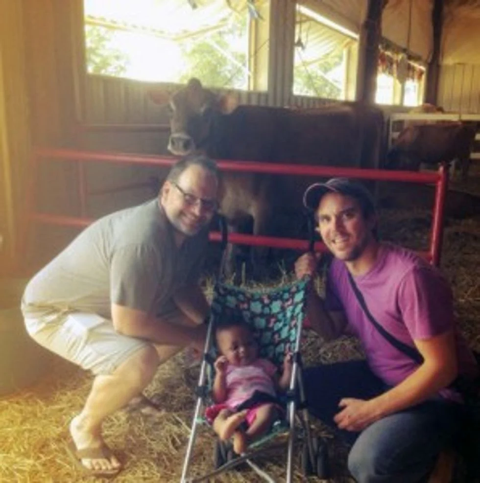 girl with her dads in a barn
