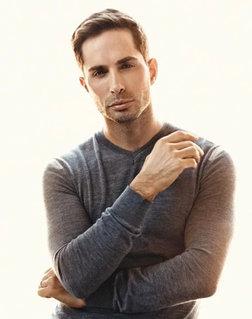 Man posing in a gray V neck sweater