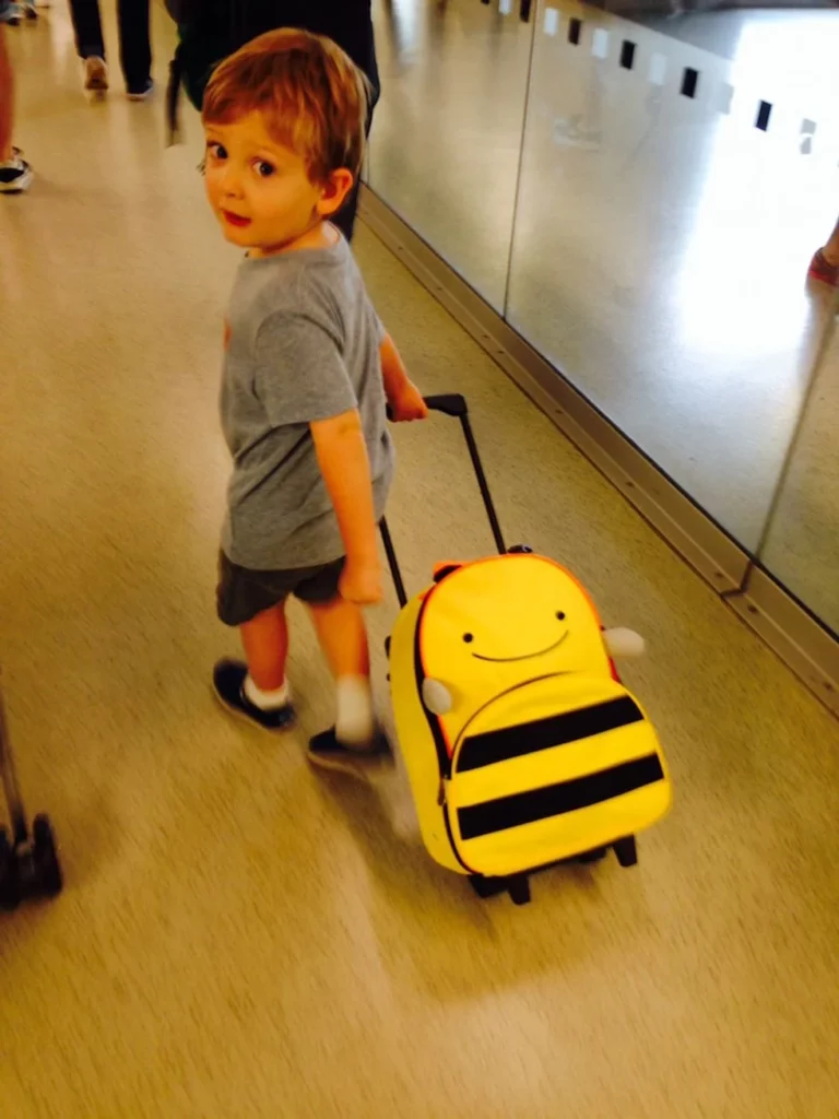 Little boy pulling his bumblebee suitcase through the airport