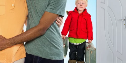 Two men hugging with a little boy with suitcases in background
