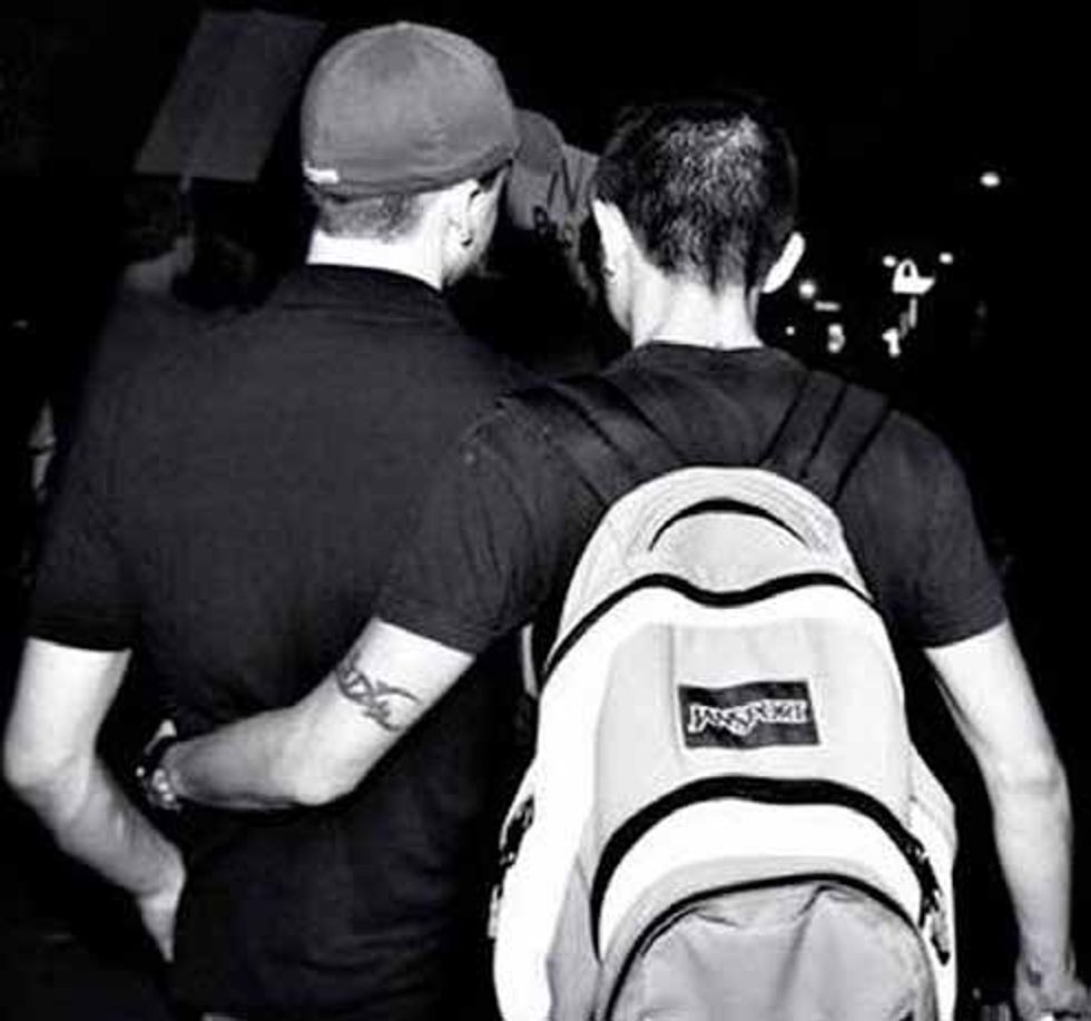 black and white photo of gay couple facing away from camera arms around each other