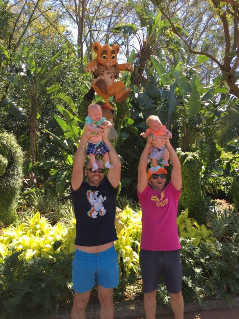 Two fathers and their two newborn sons recreating scene from Lion King