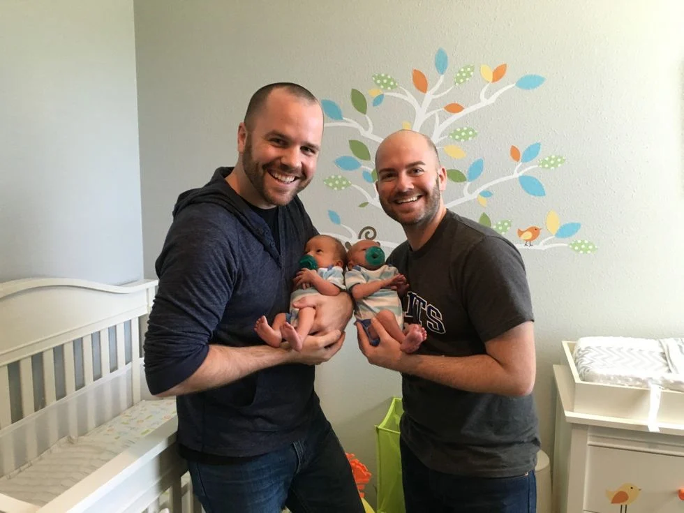 Two fathers with their two newborn sons in the nusery