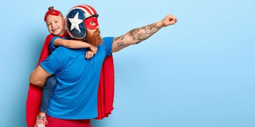 Father dresssed as superhero with child on his back
