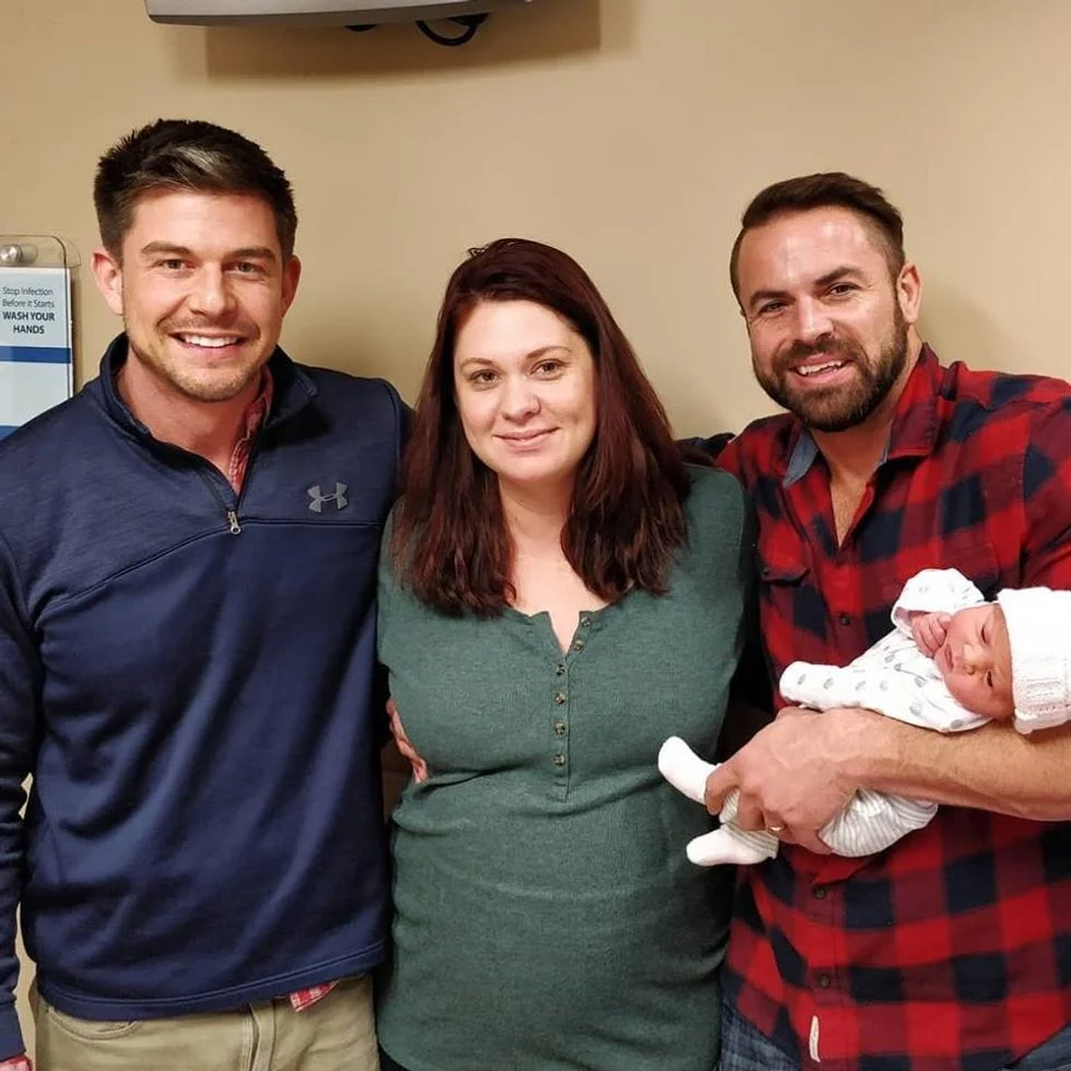 Two fathers with their surrogate and their newborn