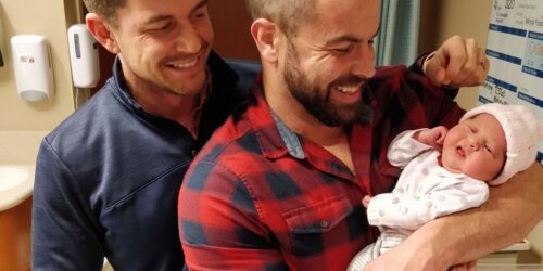 two fathers holding their newborn