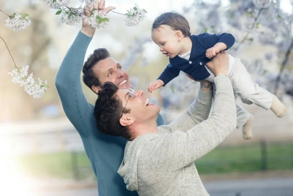 Two dads with their son under the cherry blossoms