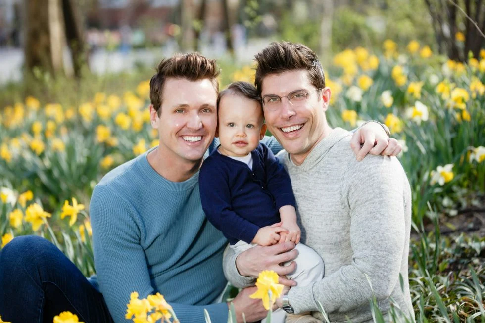 gay couple with their son surrounded by daffodils