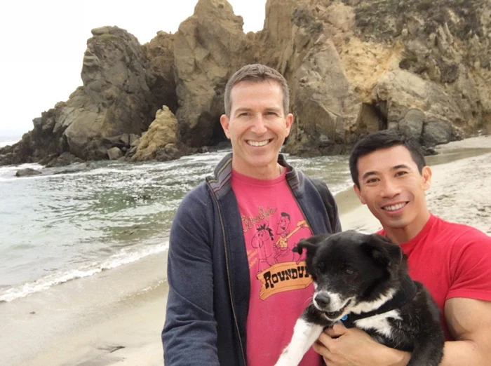 Gay couple with their dog on the beach