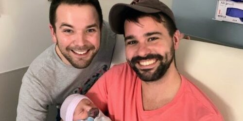 Gay dads through adoption, holding newborn baby
